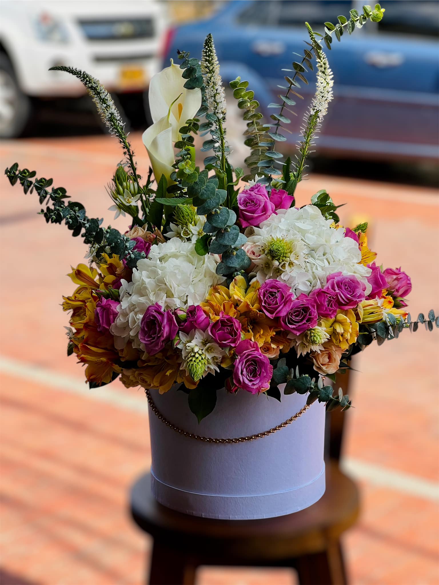 Hat box con hortensias blancas, rosas moradas, cartuchos y eucalipto